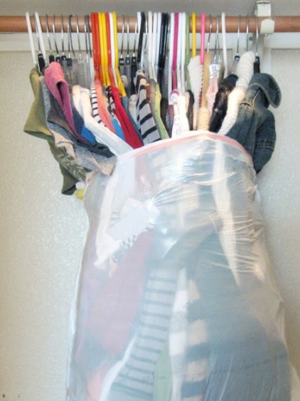 clothing on hangers stuffed into a garbage bag