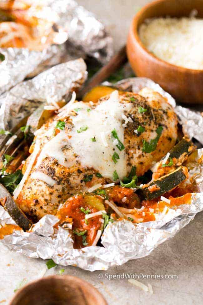 Chicken parmesan foil packets sprinkled with freshly grated parmesan and garnished with fresh parsley.