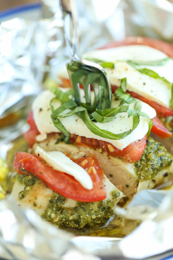 Pesto caprese chicken in foil garnished with basil
