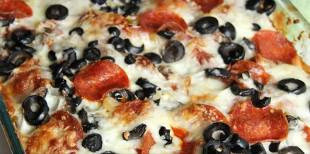 Pizza and pasta casserole topped with sliced black olives