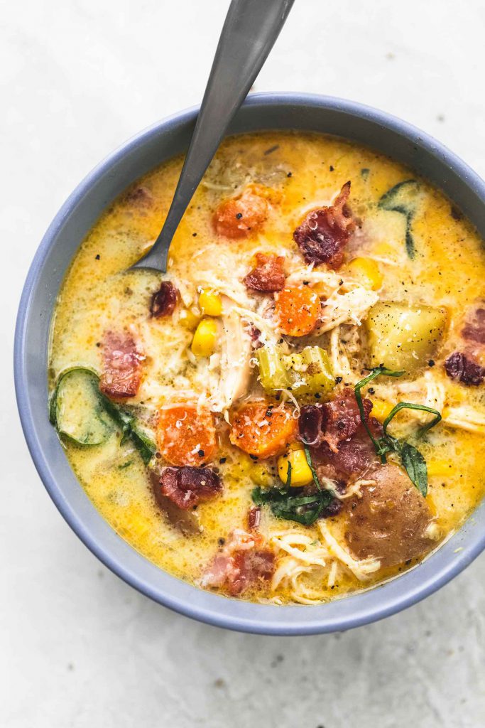 Creamylicious slow cooker New England chicken chowder. Garnished with black pepper, grated parmesan cheese, and fresh basil
