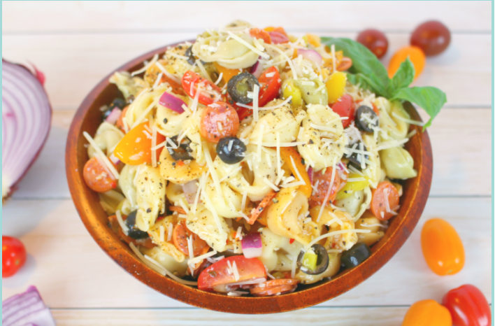 Easy tortellini pasta salad loaded with salami, tomatoes, olives, banana peppers topped with Italian dressing and shredded Parmesan cheese