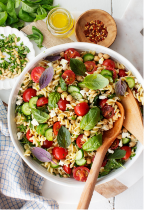 Pasta salad with cherry tomatoes, feta cheese, arugula, chickpeas, pine nuts & cucumber, and lots of fresh parsley and basil