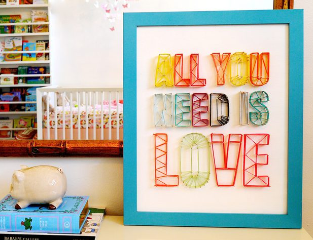 Handmade string art sign that says All you need is love