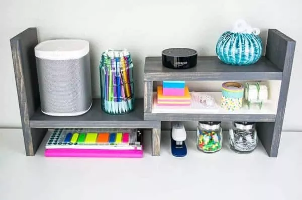 A color gray adjustable desktop organizer with some stuff on it
