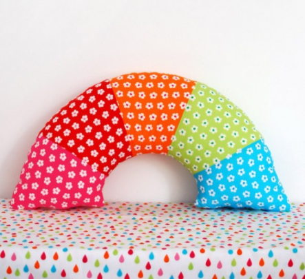 A rainbow pillow with white flowers design on it