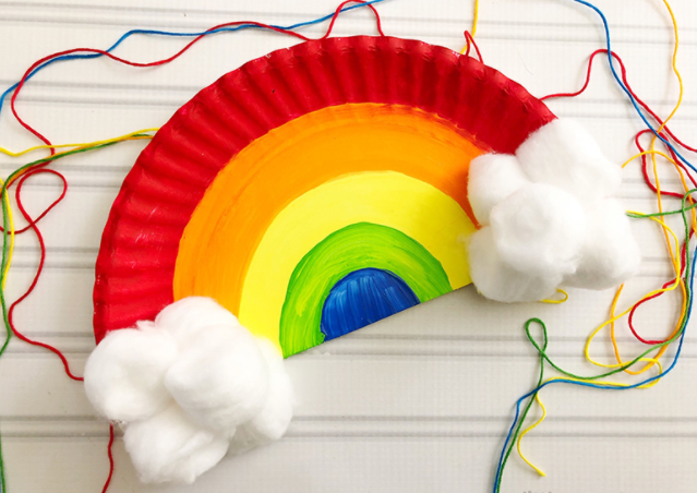 A rainbow craft made from a paper plate with some rainbow strings and cloud on it