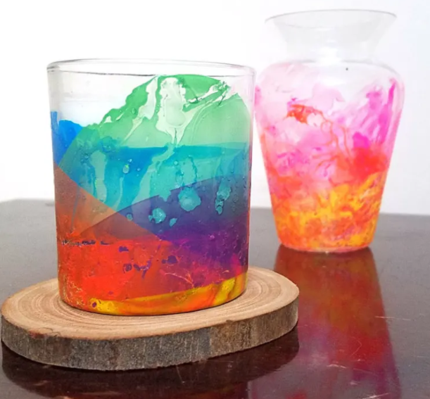 A candle holder made from glass vase painted in rainbow color 