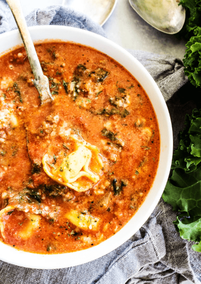 Healthy slow cooker tuscan tortellini soup garnished with more cheese