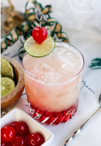 pineapple mocktail in a glass with sliced of lime and a cherry on top
