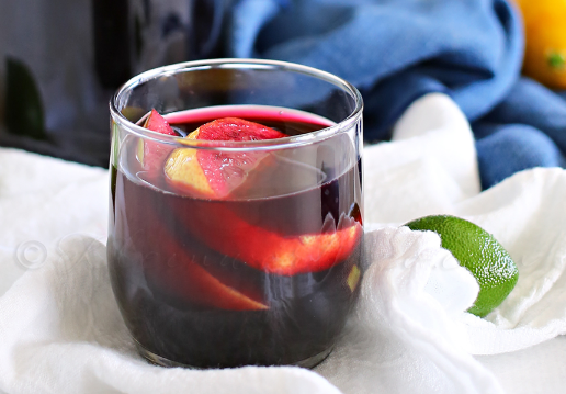 Sparkling blueberry sangria mocktail on a glass with a round slices of lemon