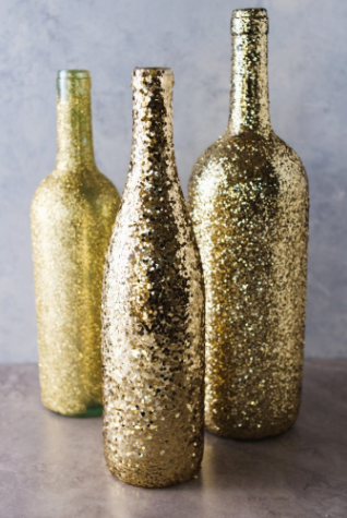 Wine bottles that have been painted gold and have glitter added to use as centerpieces
