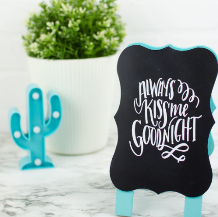 A vinyl chalkboard sign with text saying Always Kiss Me Goodnight 