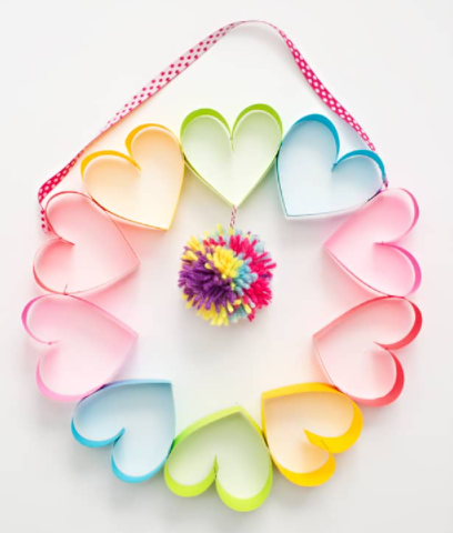 Rainbow paper heart wreath with a colorful pompom on the middle