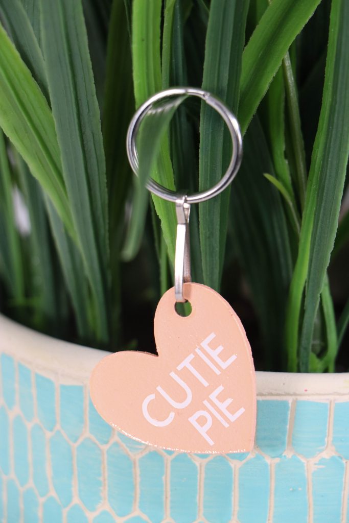 A heart shaped keychain with text saying cutie pie