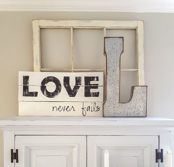 Farmhouse style wooden signs one says Love never fails and the other one is letter L