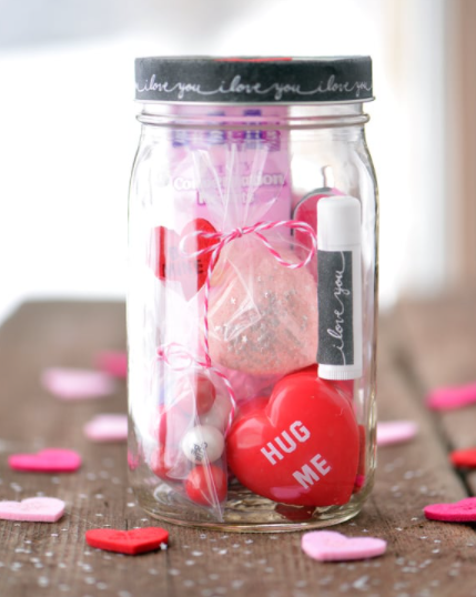 mason jar filled with items like chapstick, bath bombs, and candy - rim of jar says I love you over and over on it