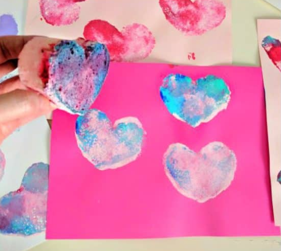 Pink paper sponge painted with lovely colors heart shapes on it.