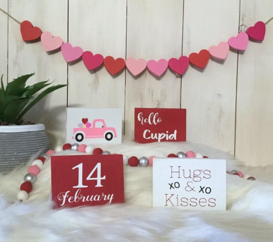 a valentine banner and four valentine's sign- one say hugs xo and xo kisses, second says hello cupid, third says 14 February , fourth has a color pink vintage truck