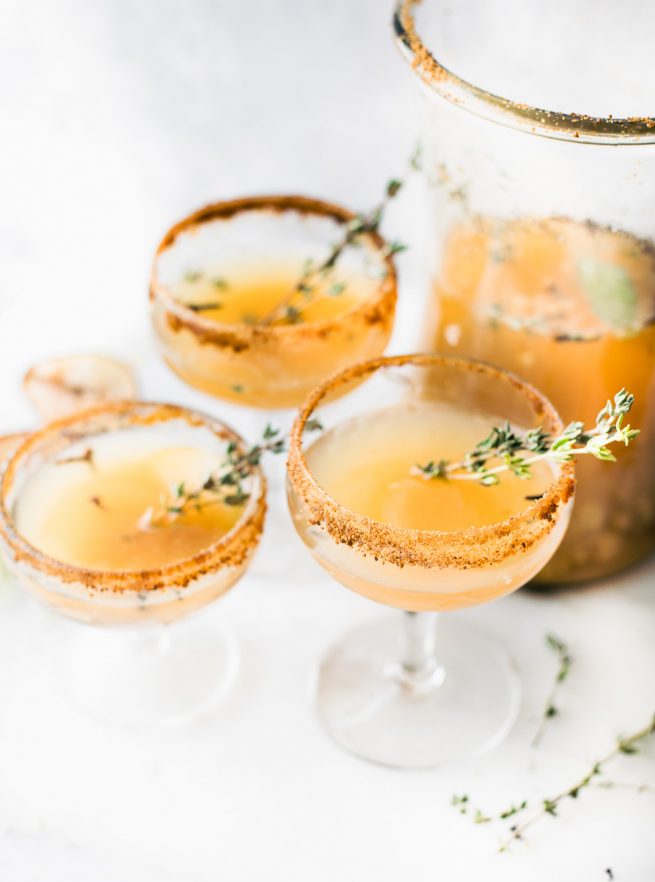 Honey roasted pear sparkling mocktail in a glass with a sprig of thyme.
