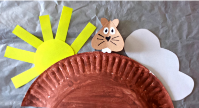 painted half a paper plate as groundhog's home, with paper groundhog, sun, and cloud
