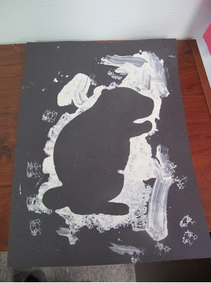 black paper with white paint to create outline of a groundhog