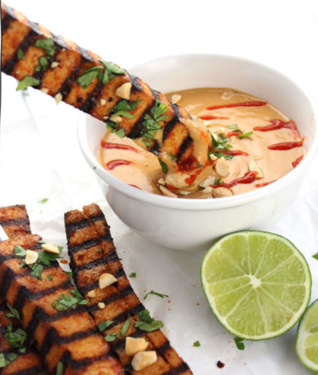 Grilled tofu skewers with spicy peanut sauce and lime on the side