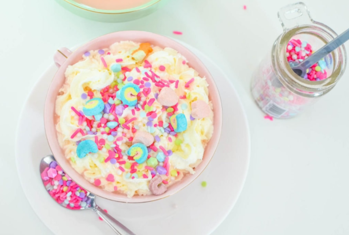 Unicorn hot chocolate topped with whipped cream and shiny candy sprinkles.