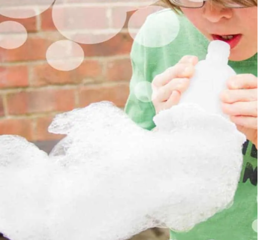 A boy blowing a bubble snake blower 