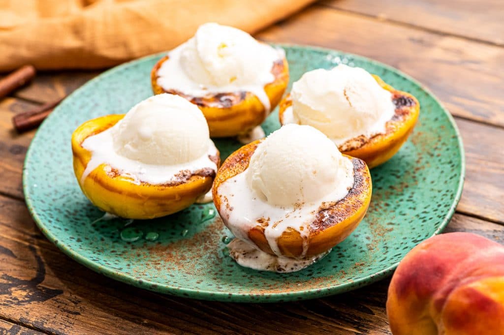 Grilled peaches top with cinnamon, honey and a scoop of ice cream a perfect summer dessert