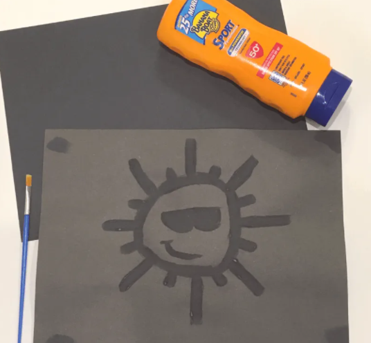 A sunscreen painting of a sun with a smiling face and a sunglass