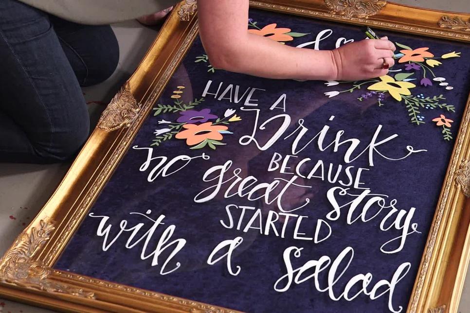 hand lettered wedding sign with random beautiful flowers design on it and text saying Have a drink because no great story started with a salad