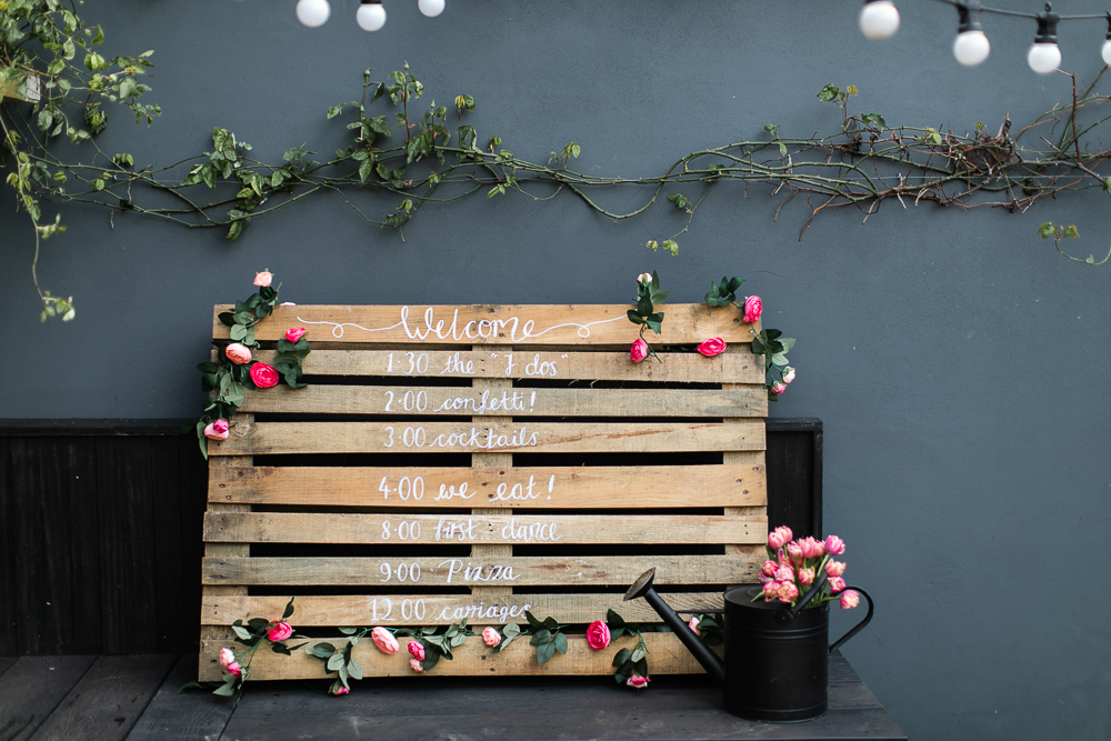 Wooden pallet wedding sign that indicates the wedding schedule