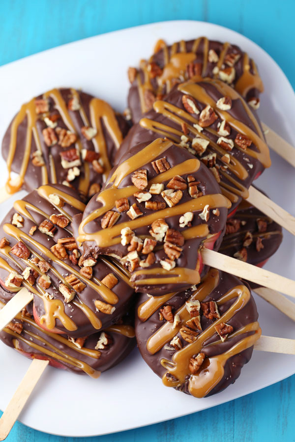 Apples covered in melted chocolate, drizzled with caramel and topped with nuts.