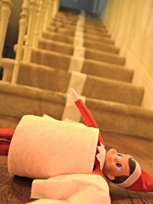 elf on the shelf being silly and having fun rolling down the stairs with napkins
