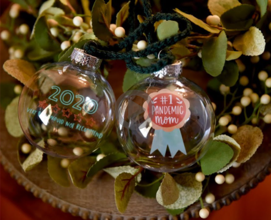 Floating Christmas ornaments. One has a number 2020, star details and text on it. the other one has a text on it saying #1 pandemic mom
