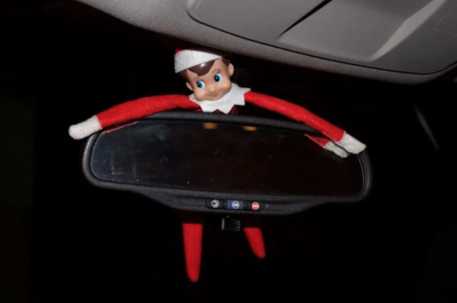 elf on the shelf hanging from the rearview mirror of your car