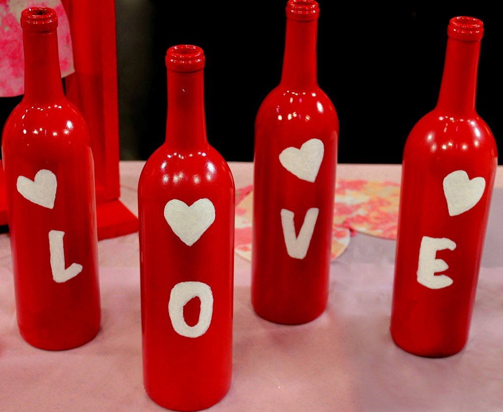 four wine bottles painted in red with heart details on each bottles and letters L O V E