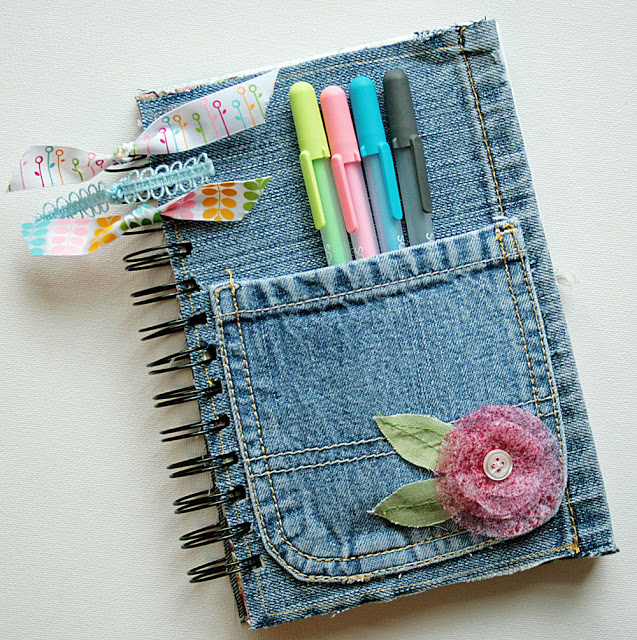 Denim covered journal with a pocket on the front and some pens 