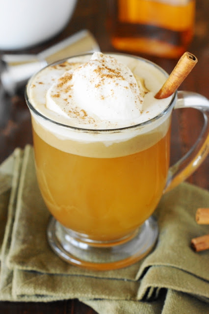 hot buttered rum topped with whipped cream and sprinkled with cinnamon in a mug