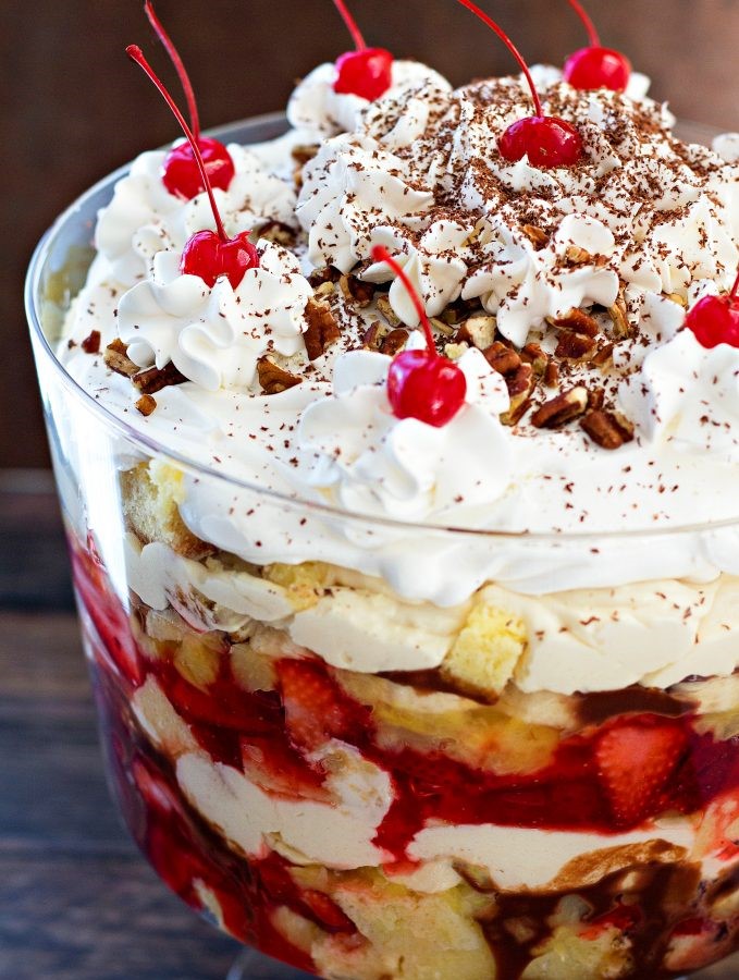 Banana Split Trifle features layers of pineapple pound cake, vanilla cream, chocolate ganache, strawberries and pineapple are all crowned with whipped cream and maraschino cherries