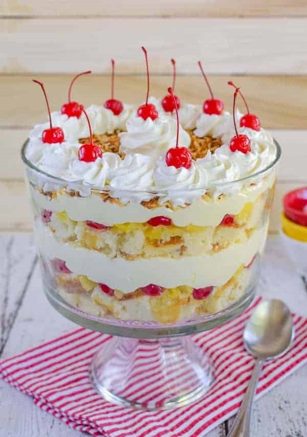 Pina colada cake trifle sprinkled on top with toasted coconut and garnished with the reserved cherries