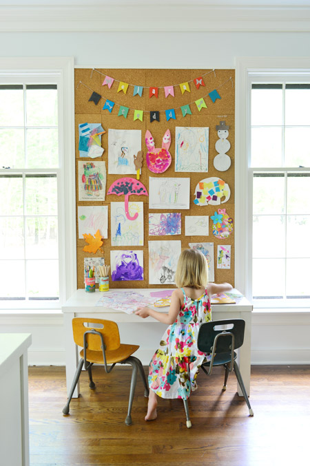 Giant cork board wall with different kids artwork on it