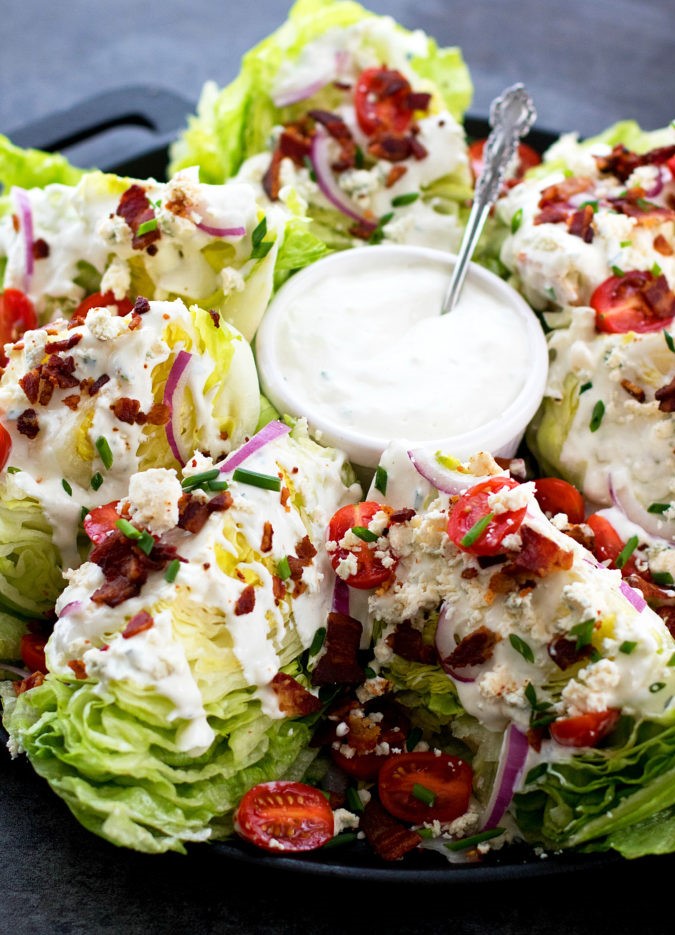 Classic Wedge Salad top with sliced tomatoes and onion. Sprinkle with bacon, remaining crumbled blue cheese and chives