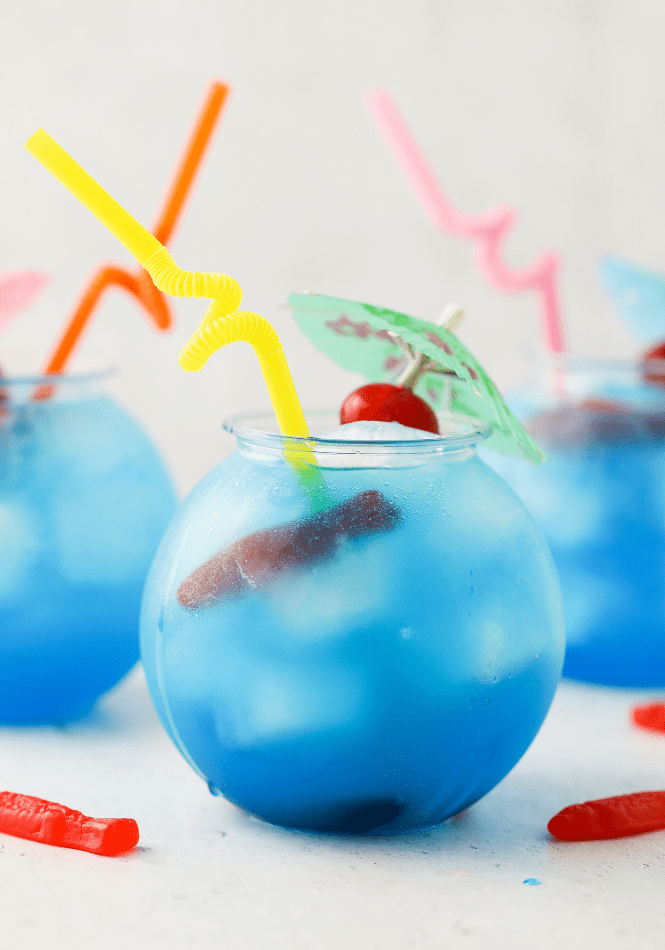 Blue Lagoon Mocktail garnished with swedish fish and a maraschino cherry on an umbrella