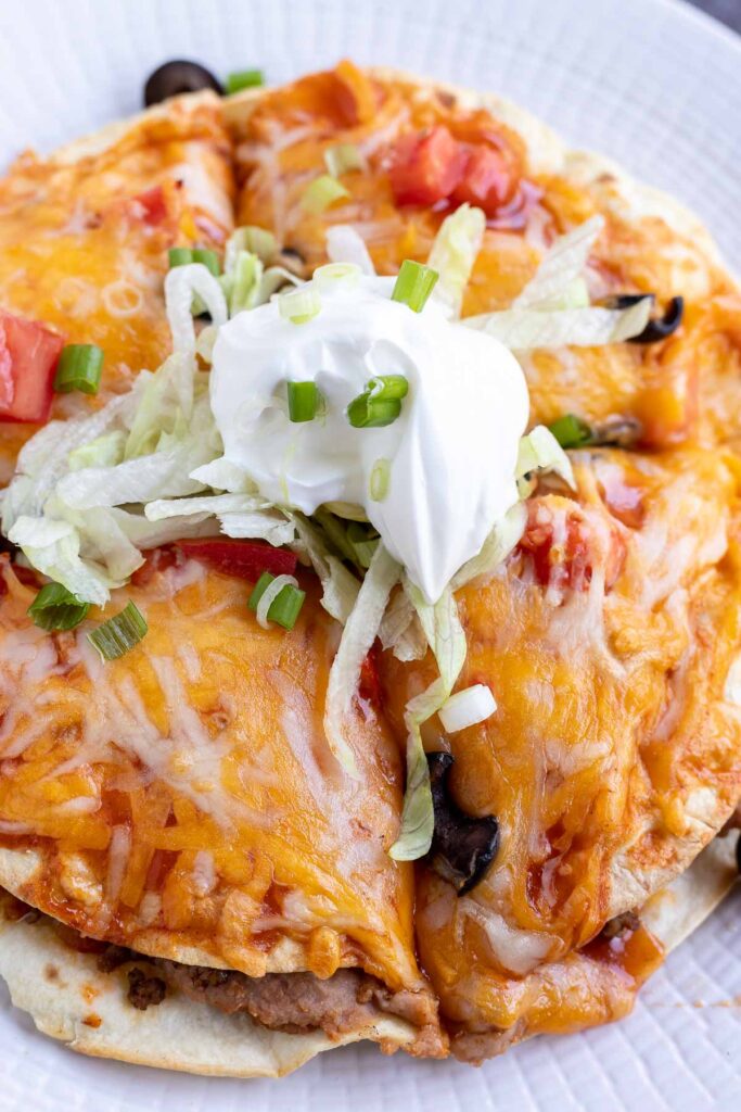 Air Fryer Mexican Pizza top with shredded lettuce, green onions and sour cream