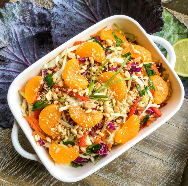 Asian Cabbage Salad with Spicy Peanut Dressing top with chopped peanuts, Mandarin oranges, and sesame seeds