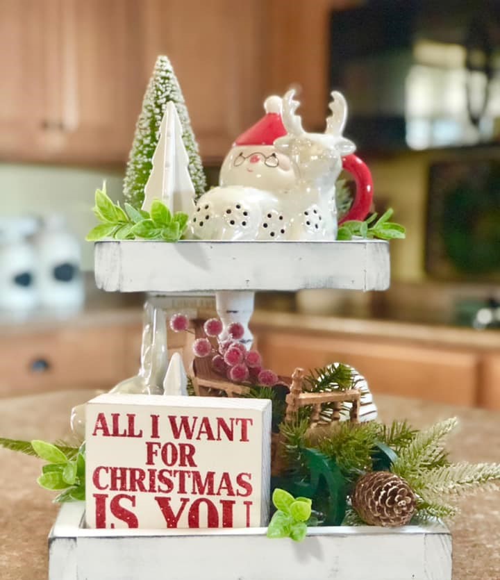 Christmas-inspired tiered tray it has salt shaker hot cocoa cup, and a red chalkboard mug and a sign that says All I Want For Christmas Is You