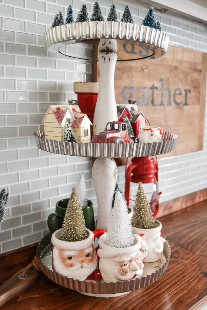 Repurposed DIY Tiered Stand that has santa mugs and other Christmas decorations on it