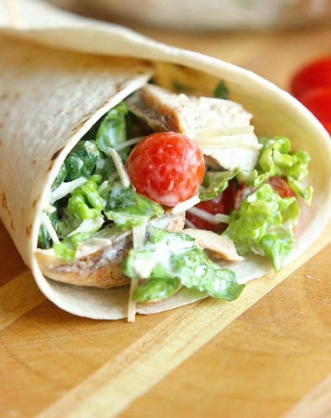 Chicken Caesar Wrap filled with grilled chicken, chopped romaine, grape tomatoes, Parmesan cheese, and caesar dressing